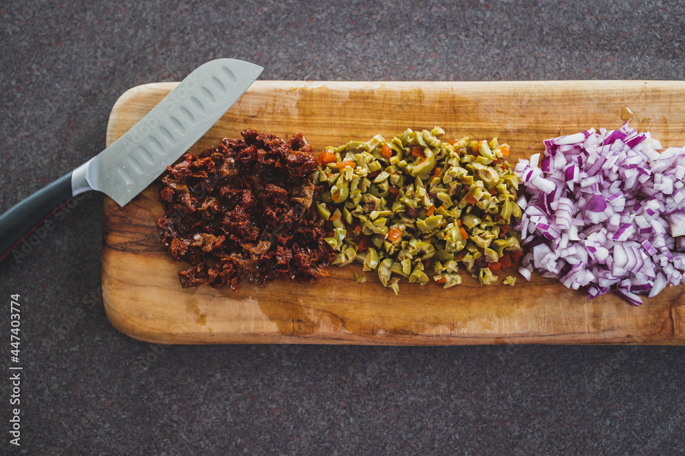 onion sundried tomatoes and oliced diced and chopped on cutting board ready to be used in a recipe, simple ingredients concept onion sundried tomatoes and oliced diced and chopped on cutting board ready to be used in a recipe, simple ingredients concept