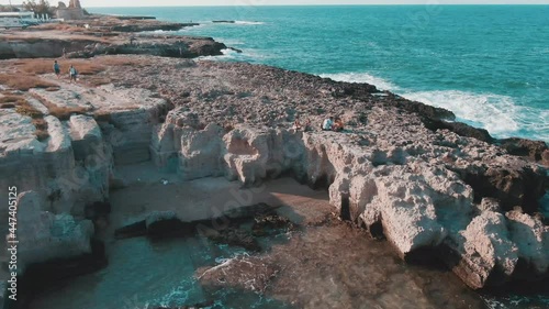 Scenery Of Coastal Cliffs With People Relaxing On Capitolo Beach In Puglia Region, Italy. - Aerial Drone Shot photo