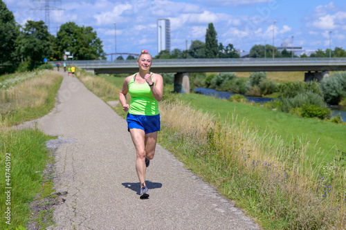 Fit healthy overweight woman jogging alongside a river