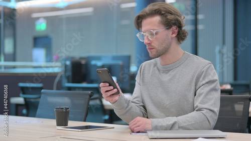 Young Man using Smartphone in Office