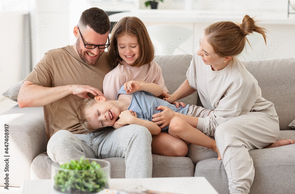 Happy beautiful family having fun and playing while relaxing on sofa in living room