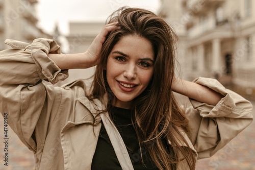 Konstfotografi Green-eyed brunette woman in beige cardigan ruffles hair