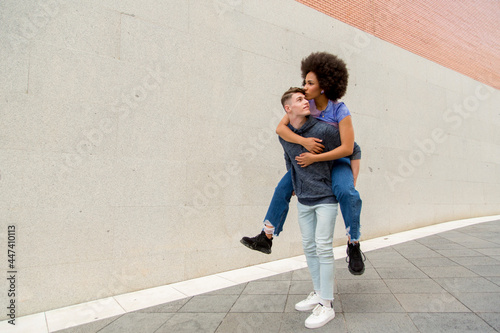 multiethnic couple Caucasian young man carrying afro woman on his back giving his a kiss © luisrojasstock