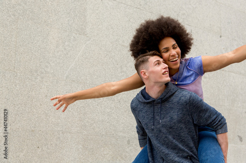 portrait multiethnic couple caucasian young man carrying afro woman on his back photo