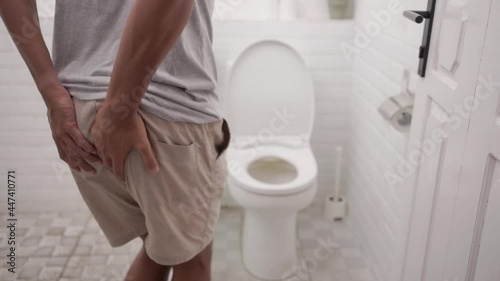 male with stomach ache having a diarrhea standing in toilet and hands hold his butt painfully.