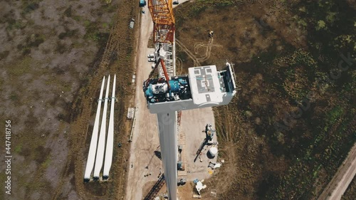 Wind generator installation. Large electric rotor installation on contemporary wind turbine by blades put on ground among rural fields aerial view