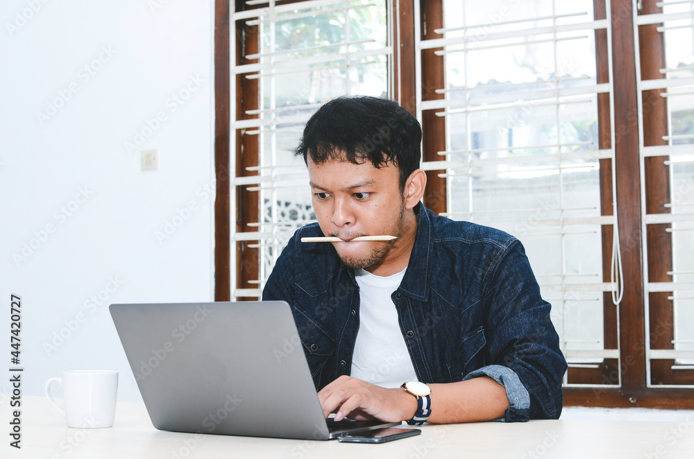 Fototapeta premium Young Asian man feeling serious when work laptop on table.
