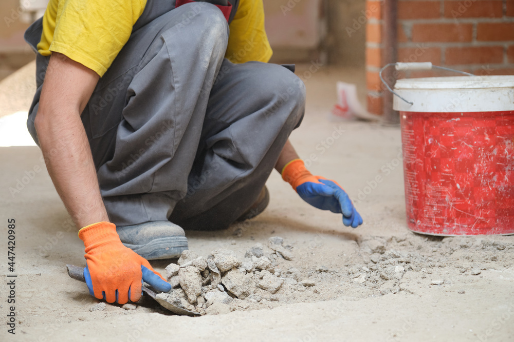 Unrecognizable young builder shoveling sand at a construction site.