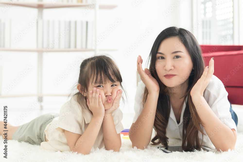Happiness Asian young mother and daughter lying on floor living room together looking at camera on holiday weekend in her house Happiness Asian young mother and daughter lying on floor living room together looking at camera on holiday weekend in her house