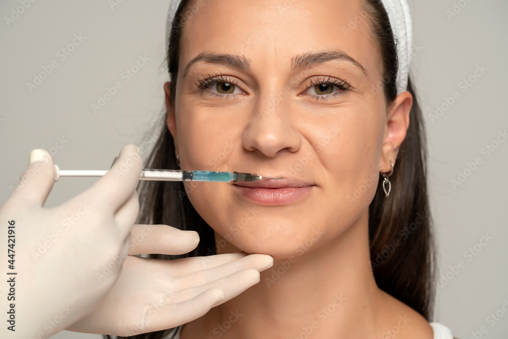 Portrait of a young satisfied woman on a lip filler injection procedure Portrait of a young satisfied woman on a lip filler injection procedure