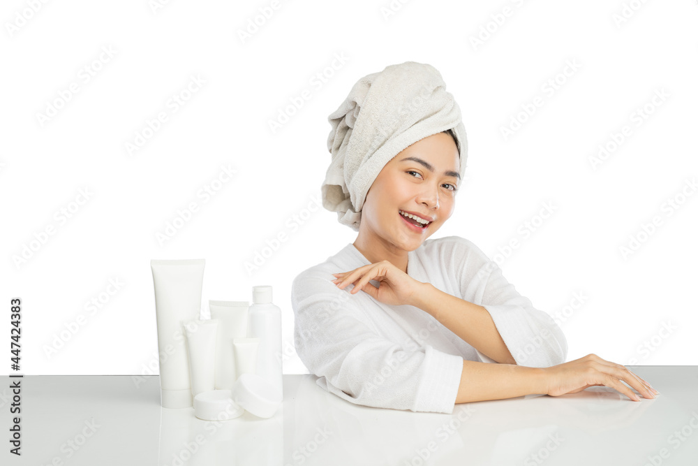 Portrait of beautiful woman wearing towel and various skin care products on table on light gray background Portrait of beautiful woman wearing towel and various skin care products on table on light gray background