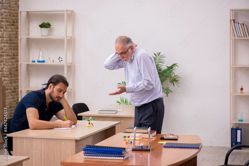 Old male teacher and young male student in the classroom Old male teacher and young male student in the classroom