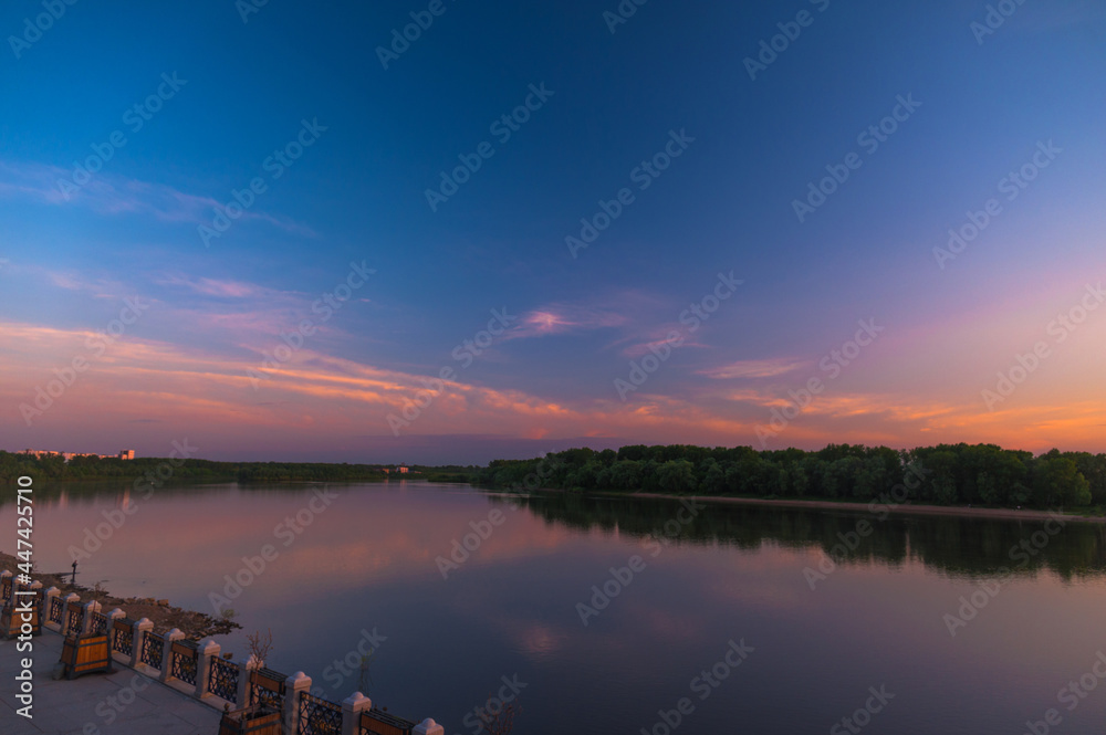 Landscape with a river and an embankment at sunset time. Photo during working hours.