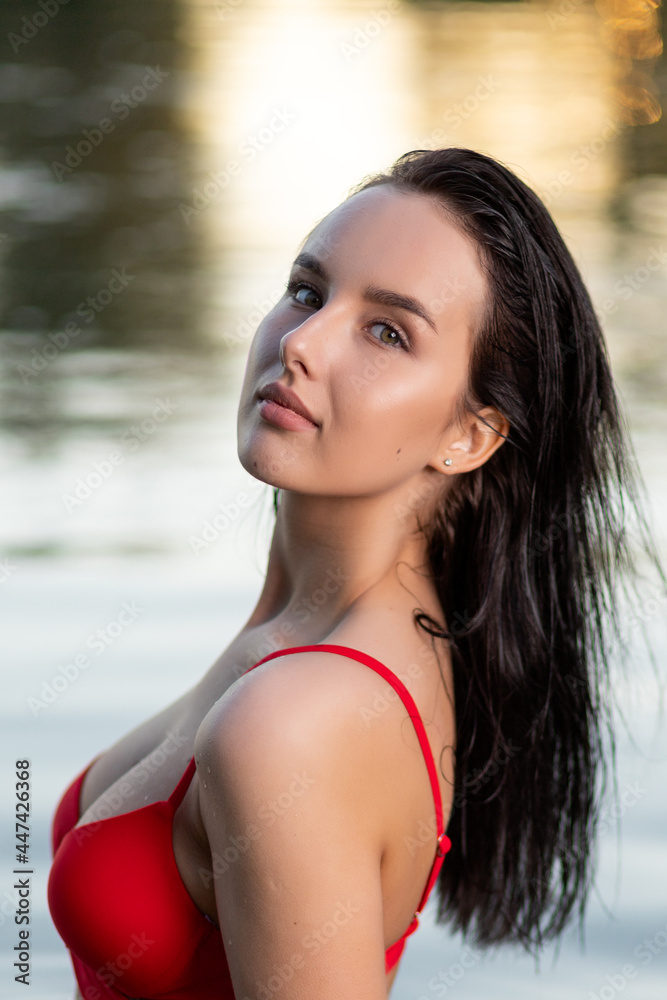 Portrait of a beautiful woman with wet hair in a sexy red bikini against the backdrop of the sea and sunset. fashionable stylish young woman on tropical beach Portrait of a beautiful woman with wet hair in a sexy red bikini against the backdrop of the sea and sunset. fashionable stylish young woman on tropical beach