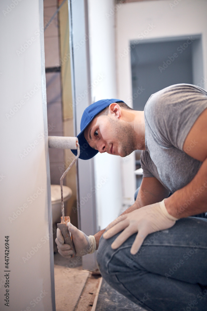 Young adult man painting on a DIY budget renovation of his new home apartment. Young adult man painting on a DIY budget renovation of his new home apartment.
