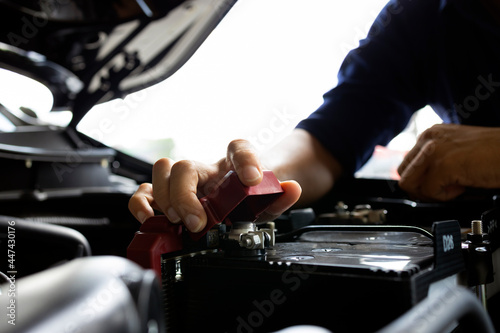 auto mechanic worker checking and changing car battery in automobile repair service center. soft-focus and over light in the background