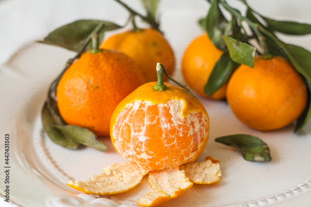 new Year's tangerines with leaves on a white plate new Year's tangerines with leaves on a white plate