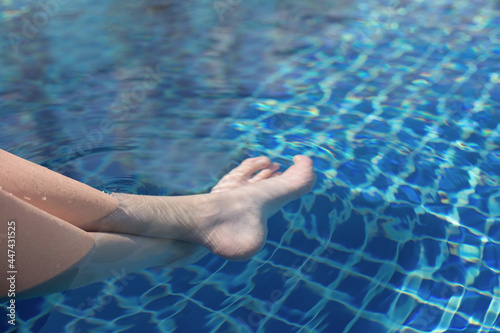 Legs of a teenager underwater in the pool. Summer rest