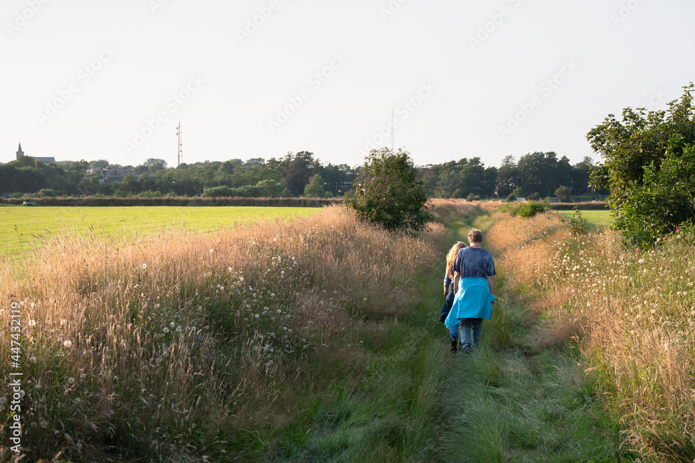 women hike on path in summer grass on dutch island of texel in holland