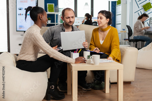 Group of diverse startup company colleague entrepreneur sitting on couch in professional workplace, brifing and sharing ideeas over financial strategy management. Employees working together at office. photo