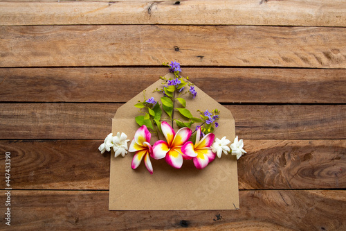 flowers frangipani, jasmine, purple and bamboo leaf arrangement in brown envelope flat lay postcard style on background wooden