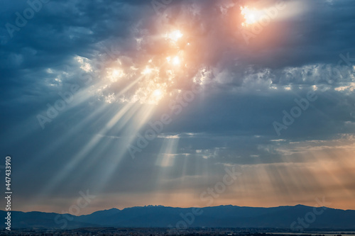 Beam of light through the clouds. Rays of light shining through clouds. Celestial entity over the city. Sign of presence of God in some religions. Ultraviolet rays concept.