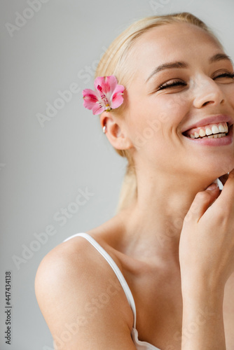 Young blonde woman laughing while posing with flower