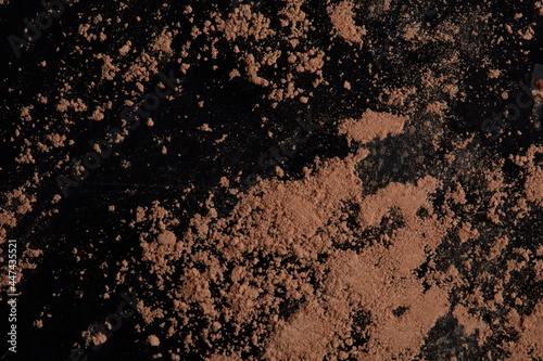 Brown cocoa powder scattered on a black background.