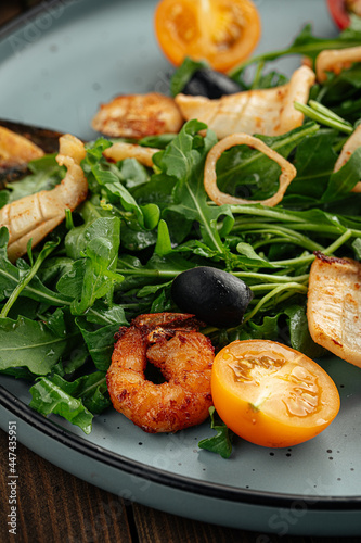 Plate of gourmet seafood salad with greens on a wooden background