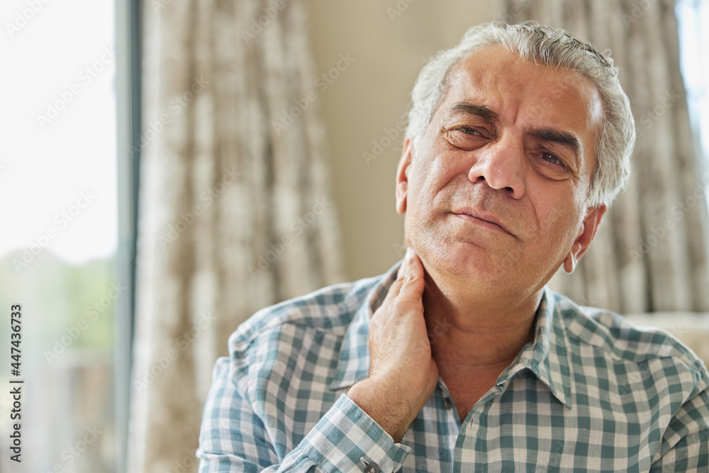 Mature Man At Home Suffering From Muscle Pain Or Ache In Neck Mature Man At Home Suffering From Muscle Pain Or Ache In Neck