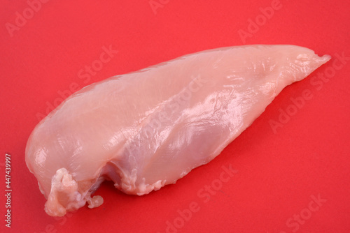 Filet de poulet cru en gros plan sur fond rouge