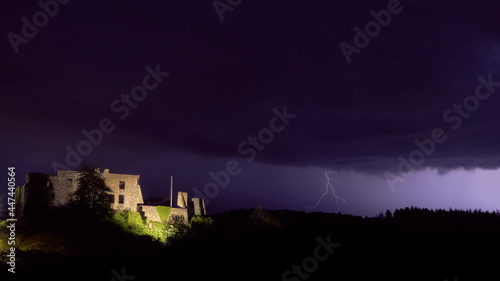 medieval castle illuminated at night with a thunderstorm overhead and lightning in the background