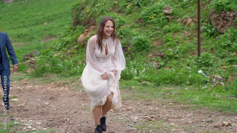 cheerful and happy newlyweds walk along a mountain path among the trees. cheerful and happy newlyweds walk along a mountain path among the trees.