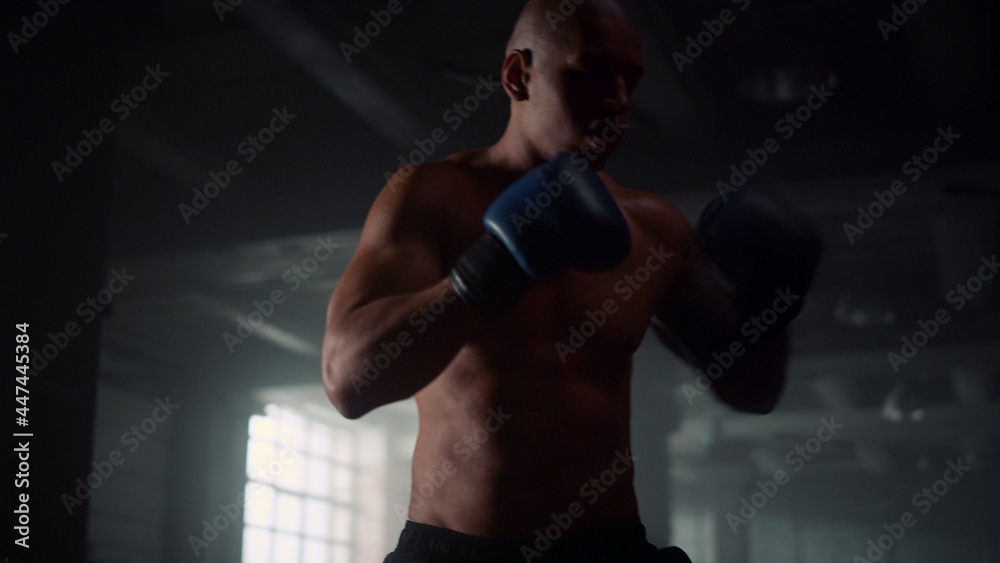 Man doing boxing training in loft building. Male fighter kicking punch bag 