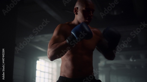 Man doing boxing training in loft building. Male fighter kicking punch bag  © stockbusters