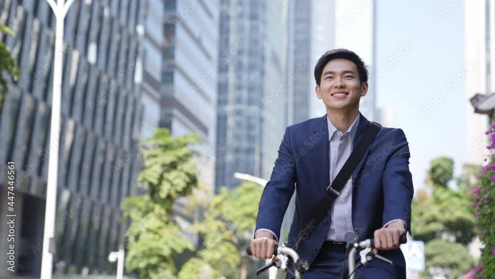 happy young asian businessman commuting by bike in modern city