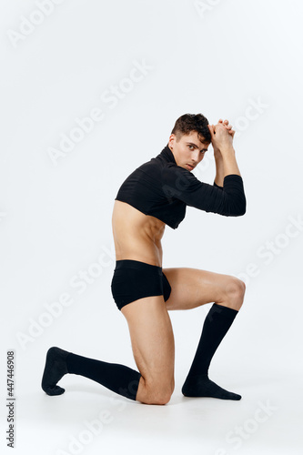  guy with pumped up muscles stands on his knee on a light background © SHOTPRIME STUDIO