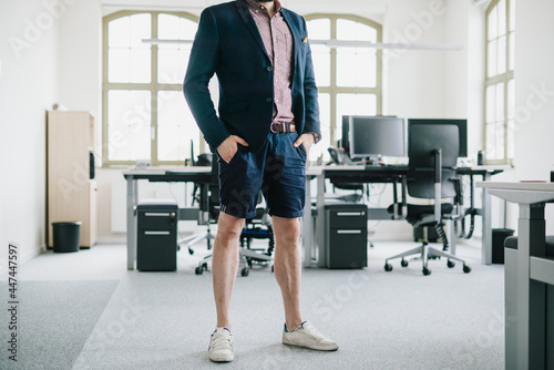 person in the office standing for desk in Shorts and blazzer