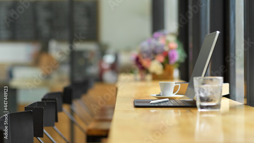 Side view of tablet, glass of water and coffee cup on wood table