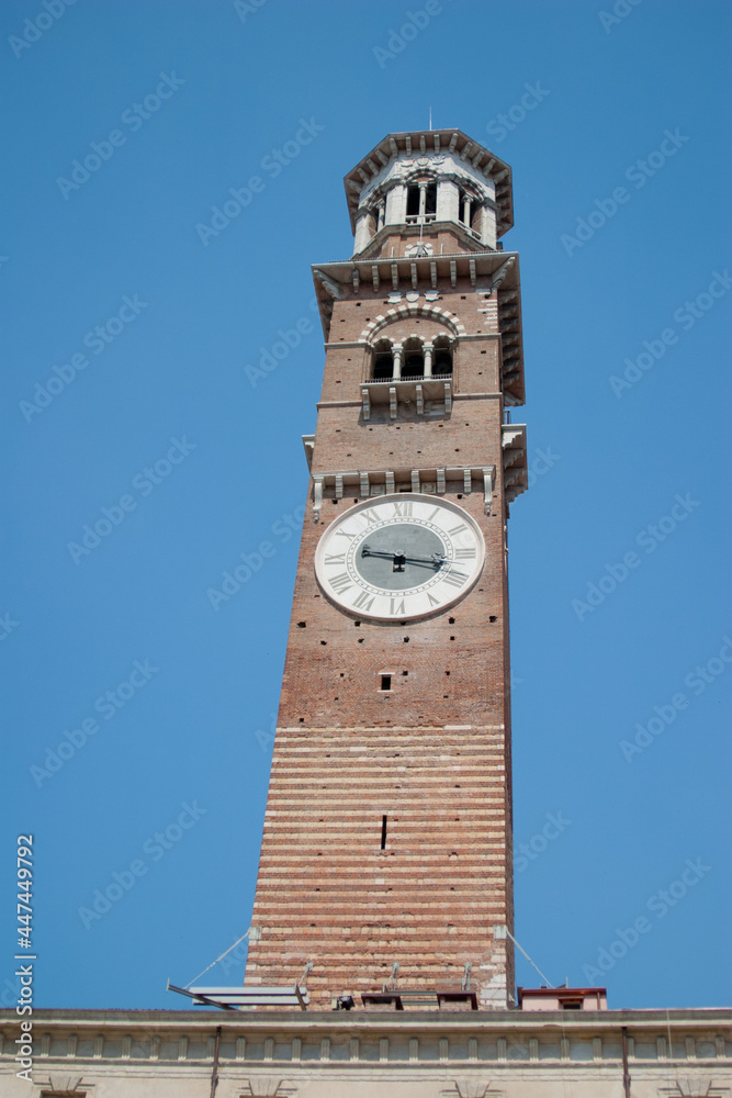 A tall and ornate brickwork clock tower in a typical Tuscan town in Italy