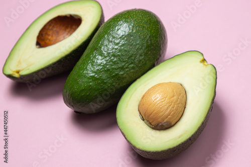 Avocado on a pink background. Cut avocado on colored background