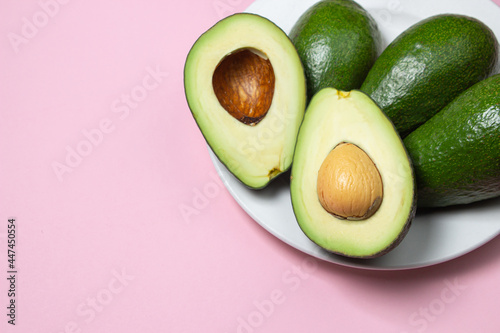 Avocado on a pink background. Cut avocado on colored background