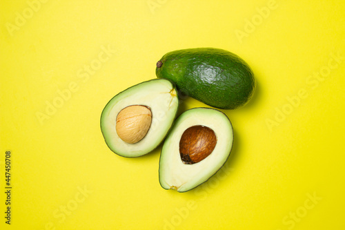 Avocado on a yellow background. Cut avocado on colored background
