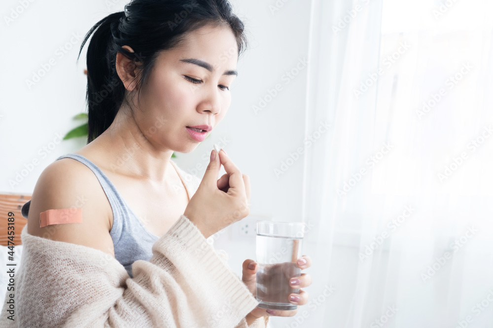 sick Asian woman taking medicine with glass of water after receiving vaccine Coronavirus ( Covid-19 ) sick Asian woman taking medicine with glass of water after receiving vaccine Coronavirus ( Covid-19 )
