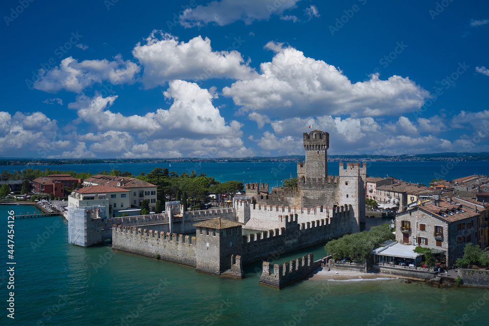 Flag of Italy on the towers of the castle on Lake Garda. Aerial panorama of Sirmione castle, Lake Garda, Italy. Italian castles Scaligero on the water. Top view of the 13th century castle.