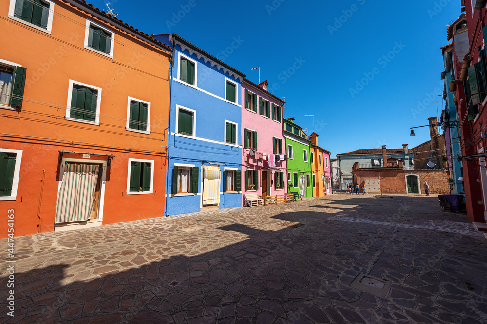 Old small beautiful multi colored houses (bright colors) in Burano island in a sunny spring day. Venetian lagoon, Venice, UNESCO world heritage site, Veneto, Italy, southern Europe.