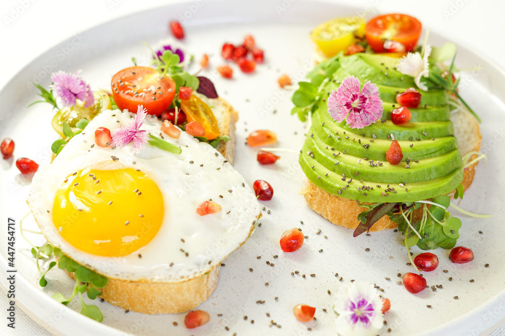 Obraz premium Healthy breakfast toast with avocado, egg, pomegranate, pomegranate and chia seeds 