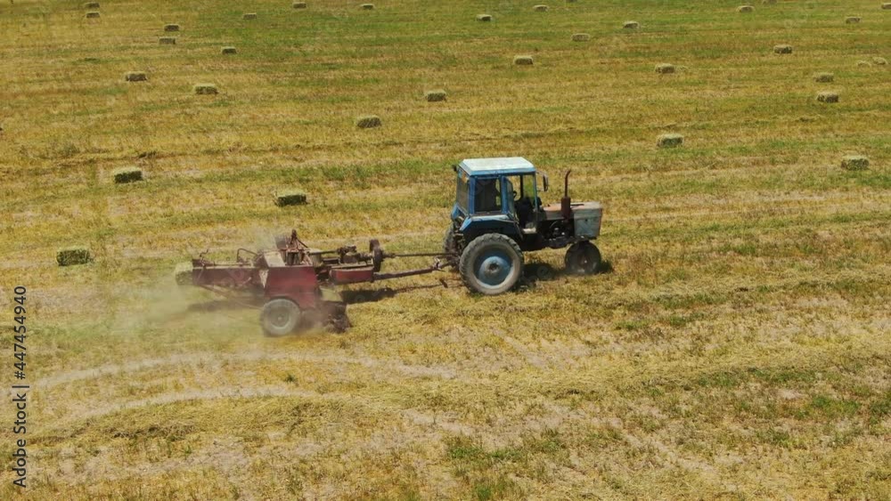 Baling Tractor Cutting Stems Of Hemp Plants To Form Square Bales At The Farmland. high angle, wide shot Baling Tractor Cutting Stems Of Hemp Plants To Form Square Bales At The Farmland. high angle, wide shot