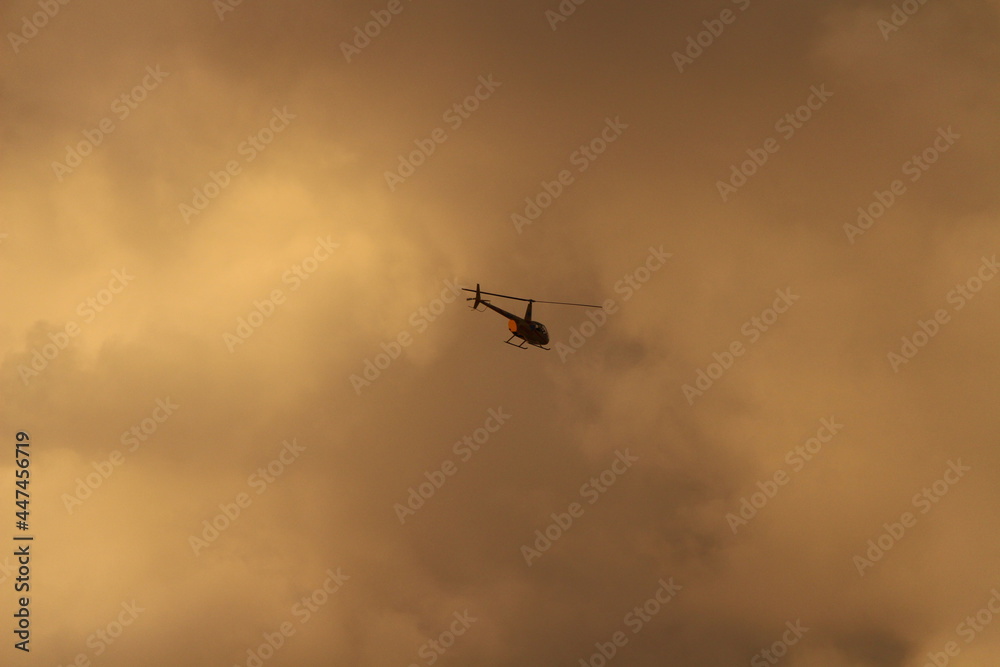 Helicopter in sky with orange clouds