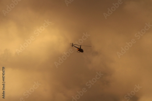 Helicopter in sky with orange clouds